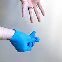 Step 3: Completely remove the inside-out glove from the first hand. Hold it tightly balled up in your remaining gloved hand.