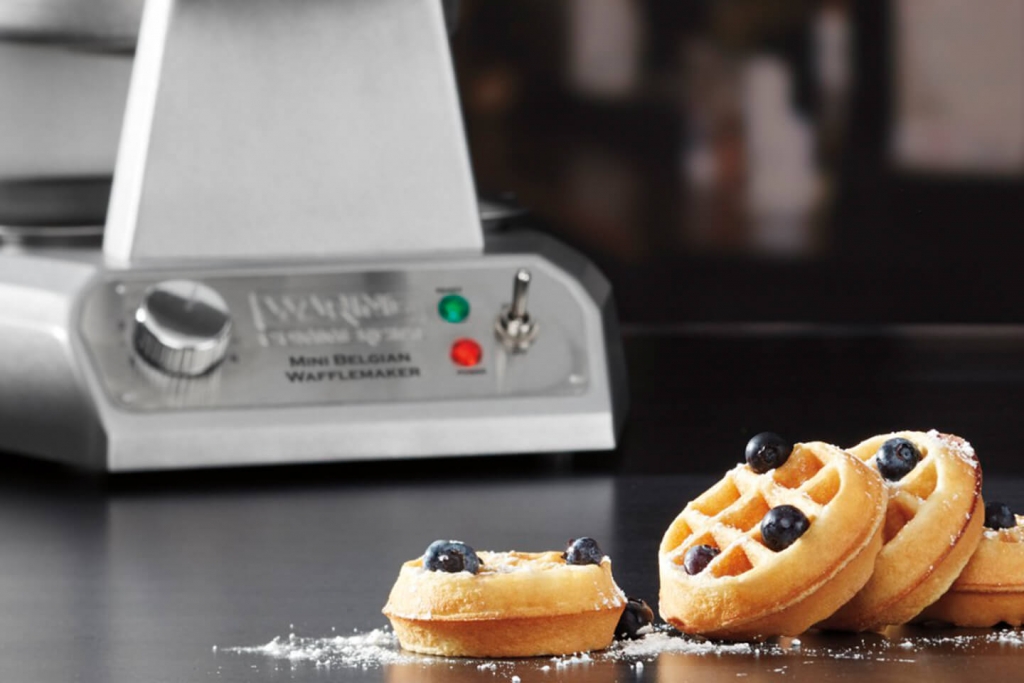 Belgian mini waffles in front of Waring's Belgian mini waffle maker.