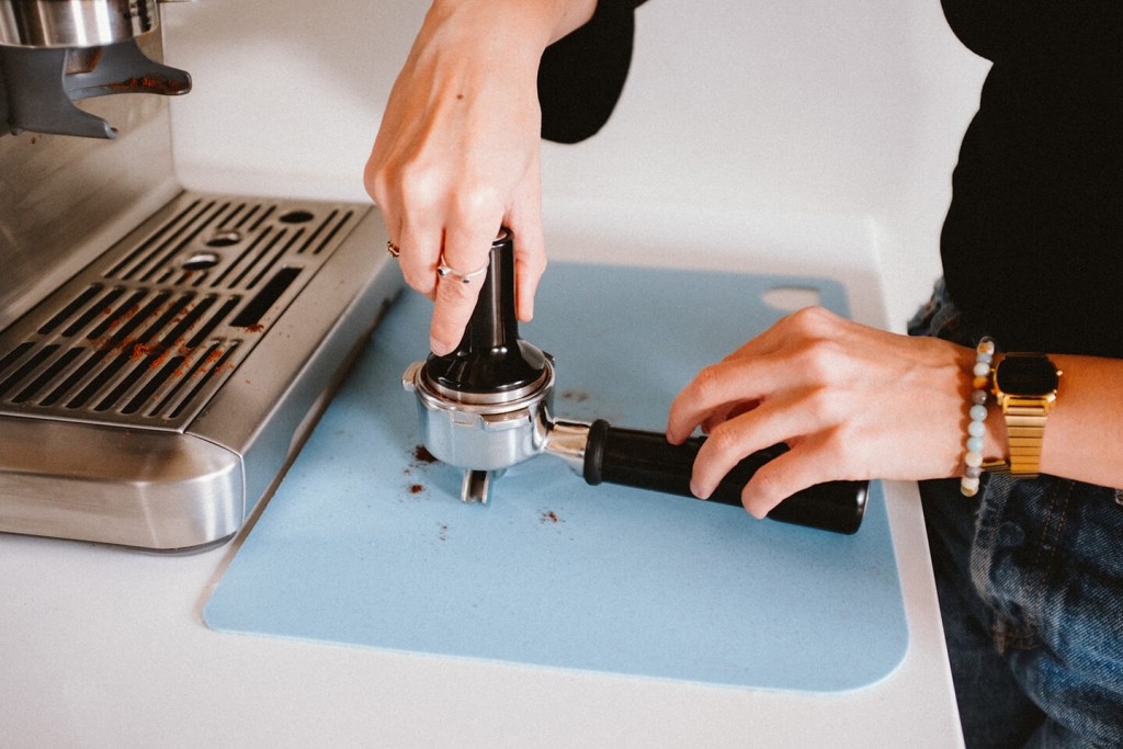 Barista tamps the grounds.