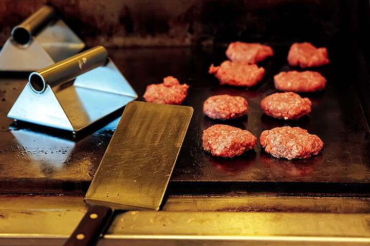 Beef cooks on a flat top griddle.