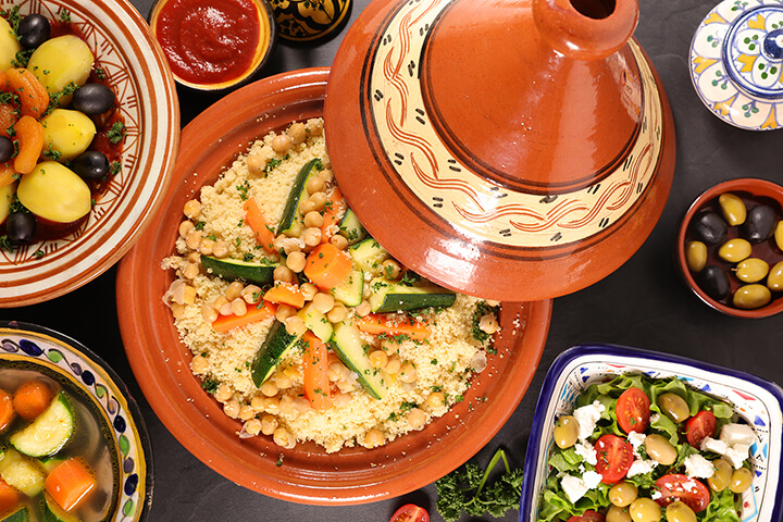A tagine with cooked chickpeas, vegetables, and cous cous.