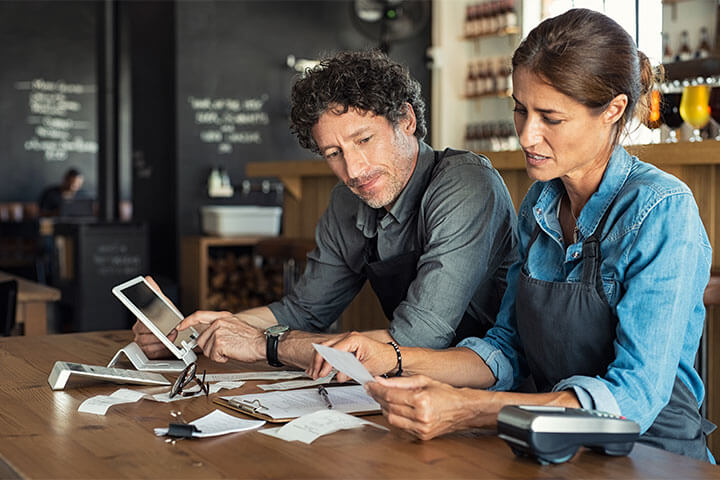 A couple who owns a restaurant together look frustrated when reviewing finances, because they just realized they hired some bad eggs.