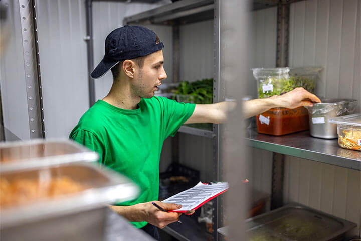 A man investigates the state of inventory in a walk in cooler.