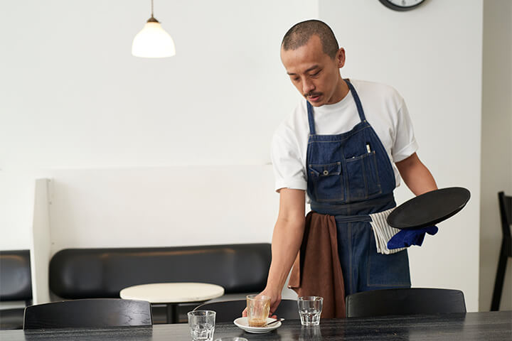 A sad employee cleans off a table.