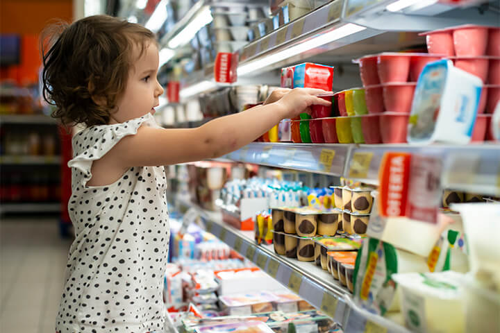 A child reaches for toxic chemicals, aka food products, in the grocery store.