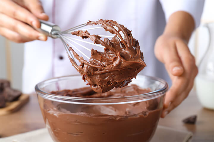 A balloon whisk whisks away dessert and is covered in chocolate. 