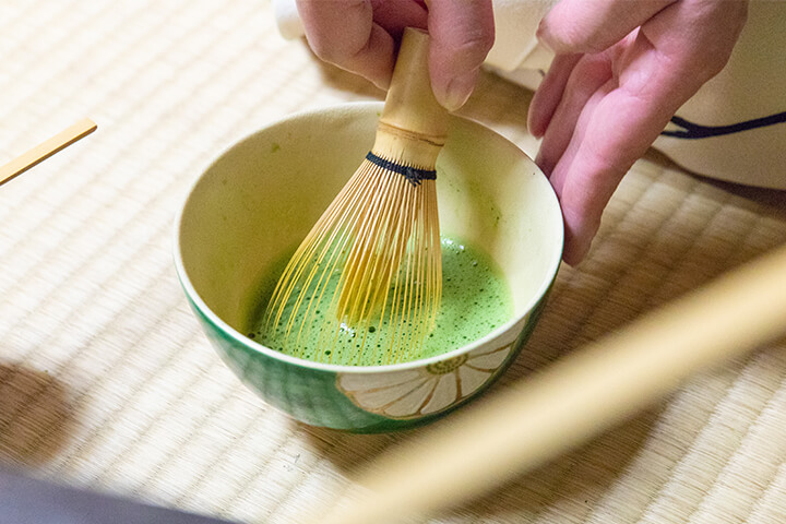 A Japanese chasen froths matcha.