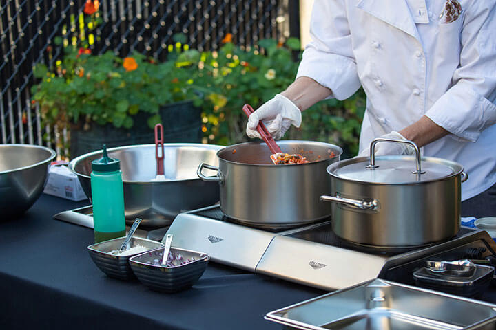 A chef uses Vollrath induction cooking productions outdoors, with ease.