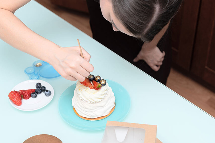 A woman works on a cake.