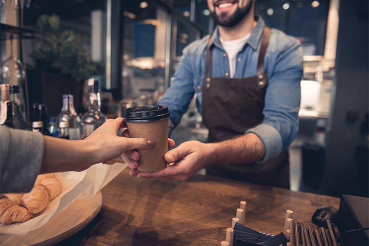 A barista hands over a hot, steamy cup of mushroom coffee.