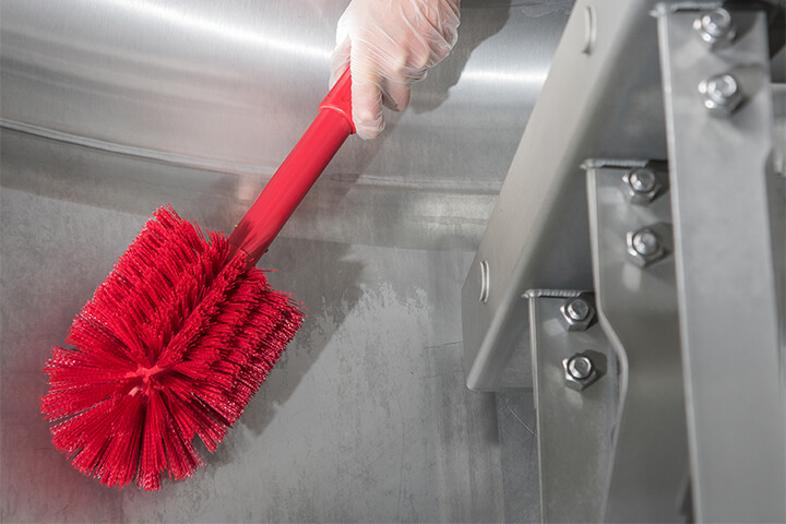 Cleaning with a red bristle brush.