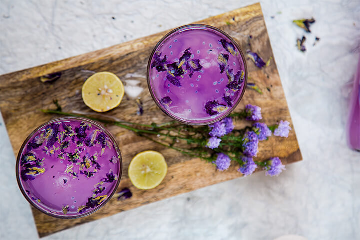 Purple drinks served to staycationers on a wooden board.