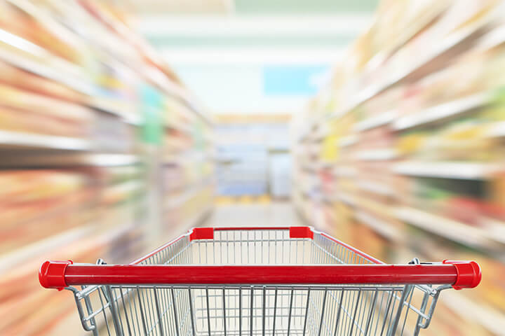 A shopping cart whirling down an aisle at a grocery store, representing the passage of time from the advent of food brokers to the present day.