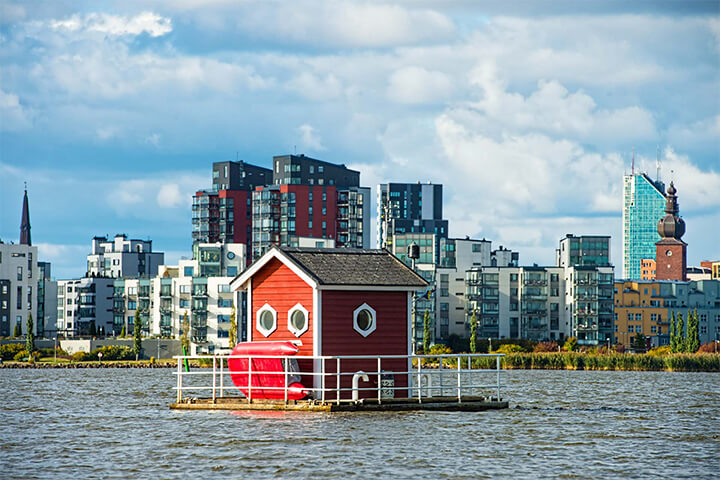 View of the little red cottage floating on a pontoon. An unconventional hotel.