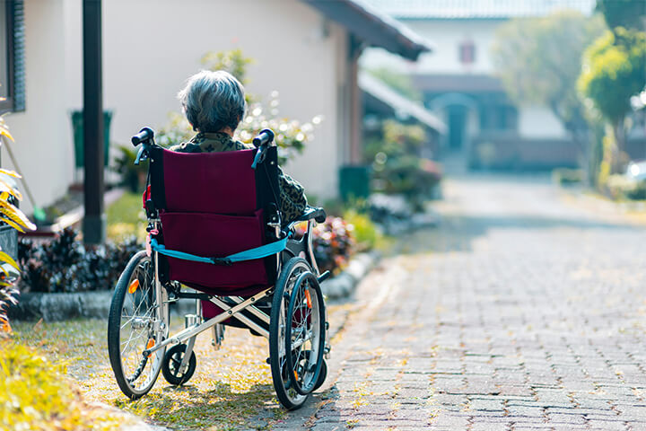 An elderly woman sits alone in a wheelchair.