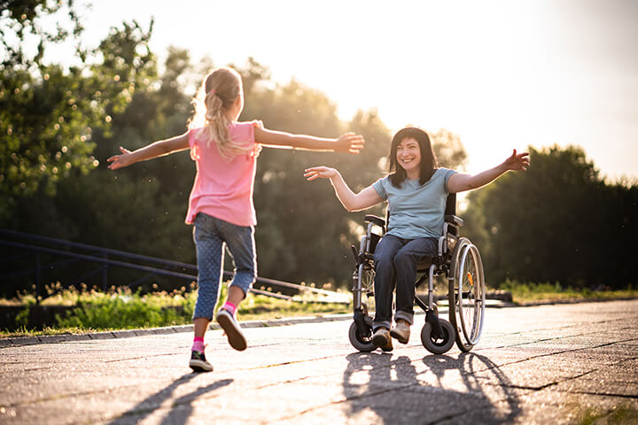 A young girl greets an adult in a wheelchair.