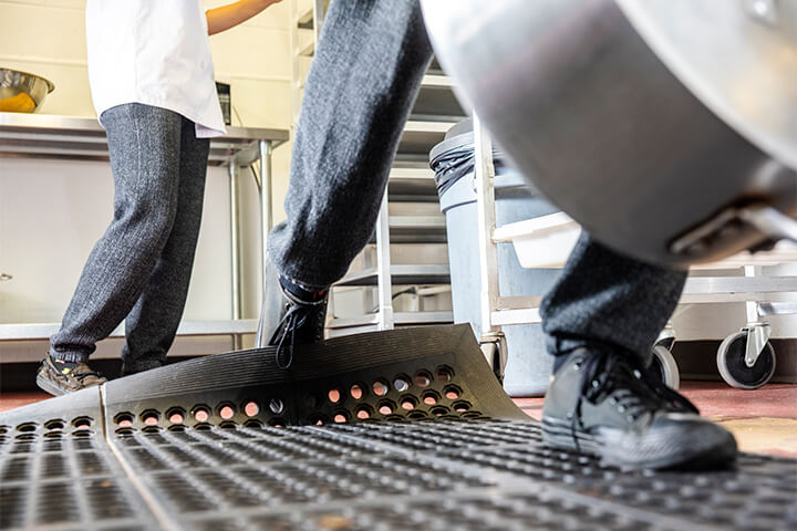 A restaurant worker trips on a floor mat.