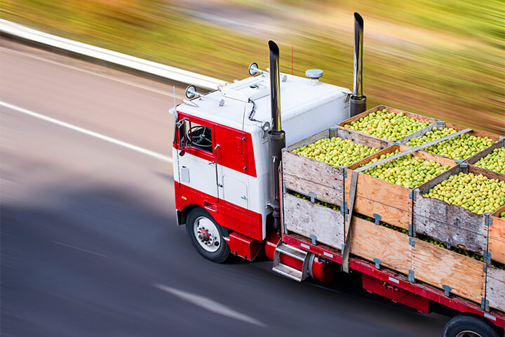A truck transports many crates of fruit.