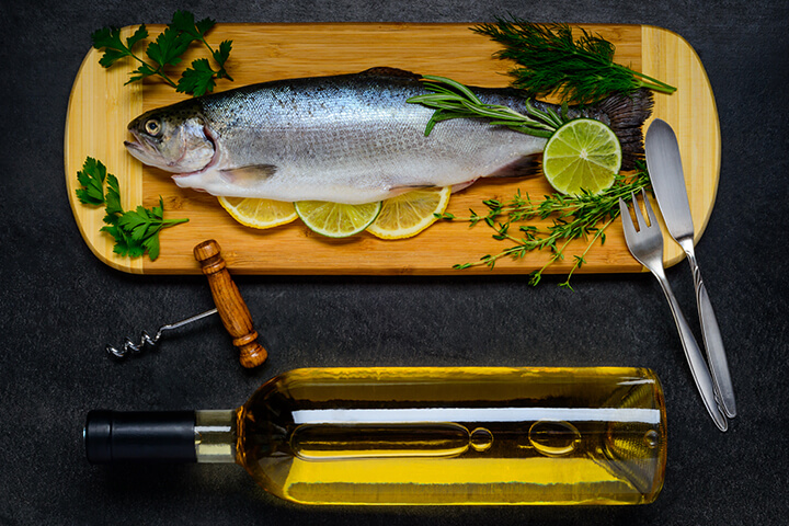 A whole fish and wine presentation featuring a fish knife and fork.