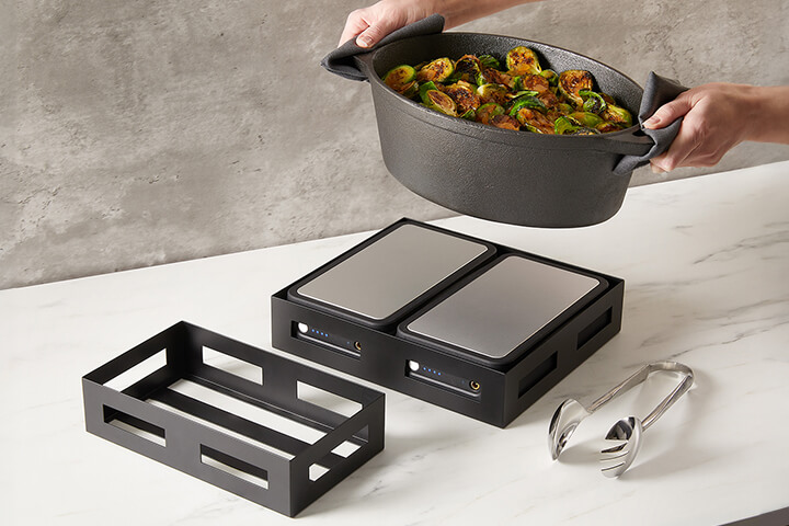 BuffetBoost Warming Blocks shown with Black Twilight Stainless Steel Crates, a Cast Iron Casserole Pot in black, and Amano Hand-Forged Serving Tongs.