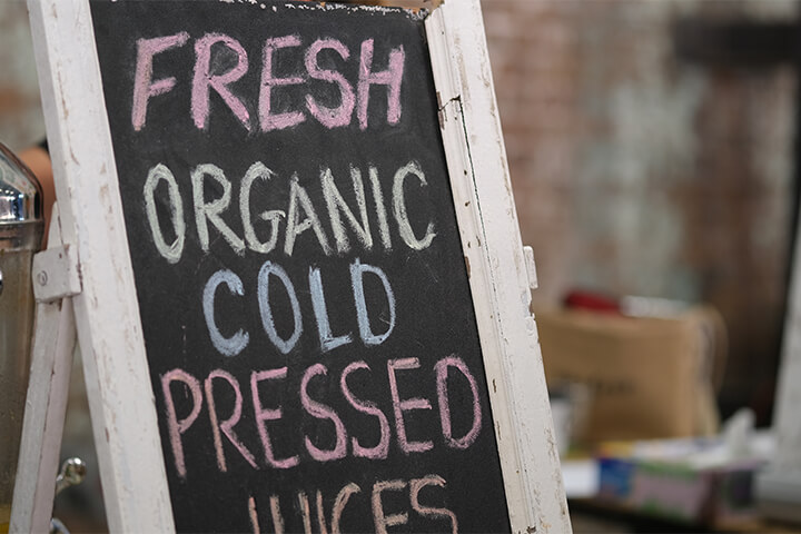 A sign with the words fresh, organic, cold pressed juices.