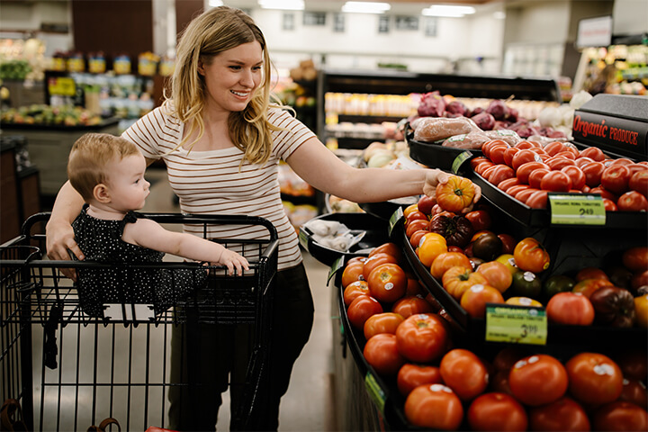 Mom and adorable baby look around the organic produce section.