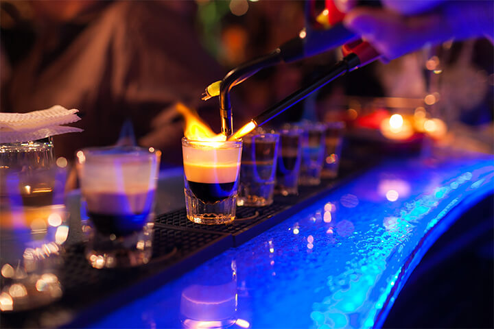 A barkeep lights a drink aflame.