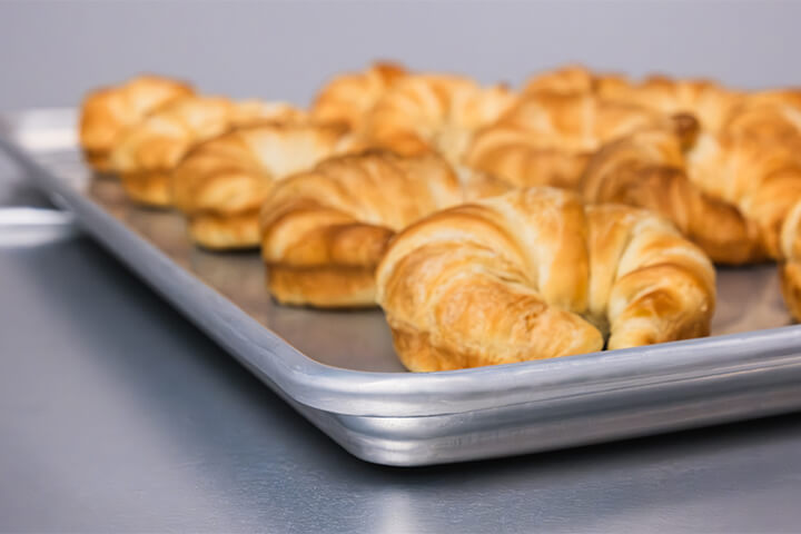 Baked croissants on a sheet pan.