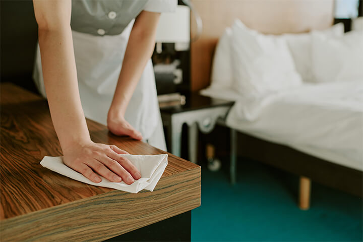 Hotel maid cleans the dresser.