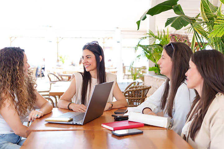 Four women talk at a table.