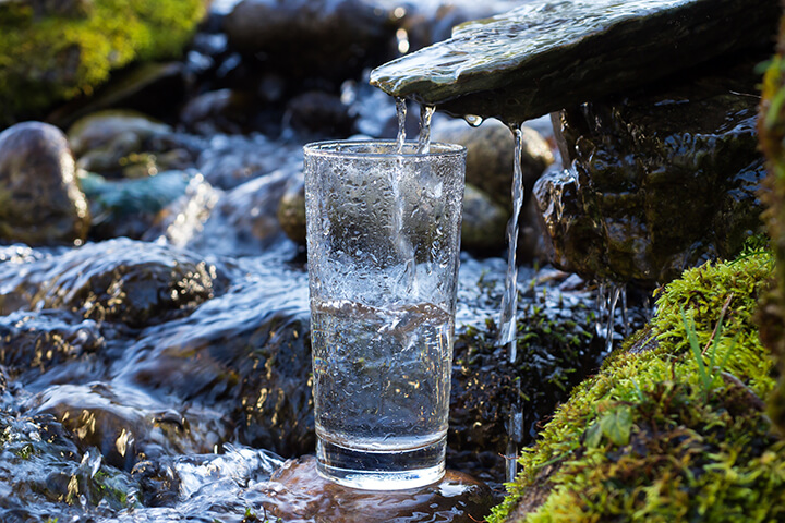 A water glass collecting water dripping from stone. 