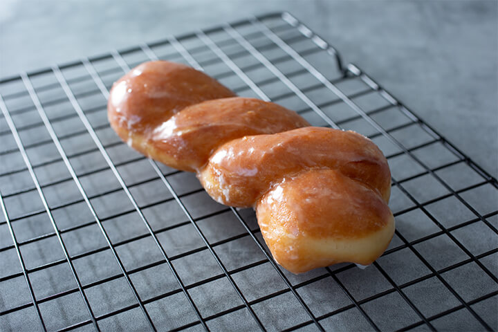 A glazed pastry sits atop a wire rack.