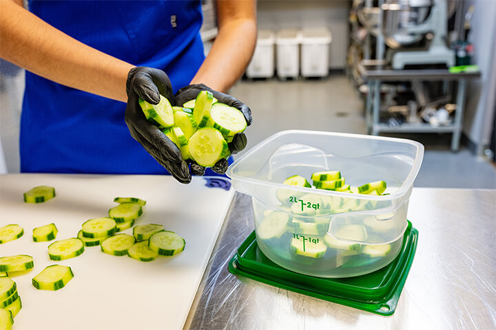 A woman preps cucumbers with her FreshPro container.