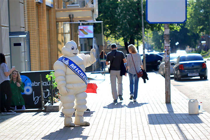 Michelin Man waves to people on the street, while wondering if he should take a note from Kool Aid Man and bust through some walls. 