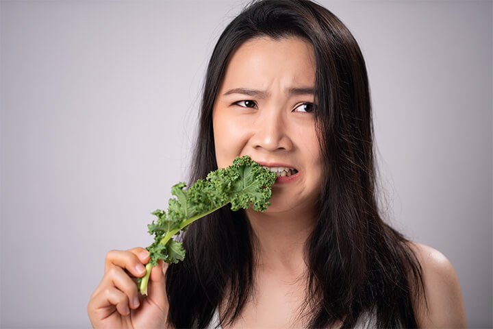 A woman eats kale. 