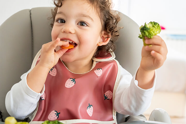 Adorable baby eating vegetables. 