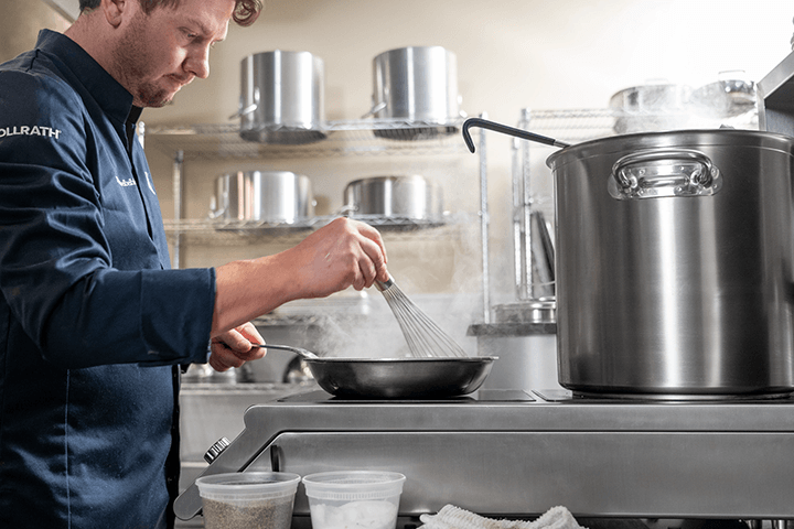 A chef stirs chocolate in a pan on an induction unit.