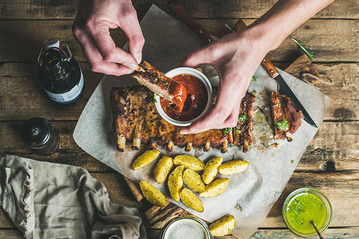 A person dips meat into sauce.