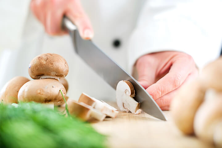 A chef cuts mushrooms.