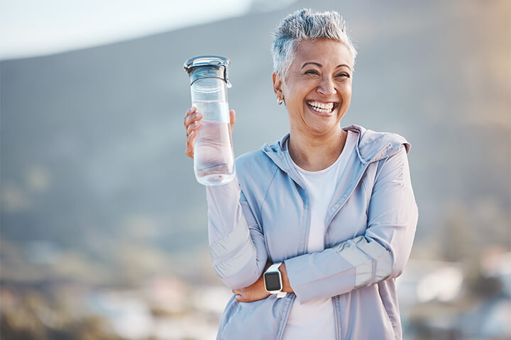 A woman smiles with a water bottle.