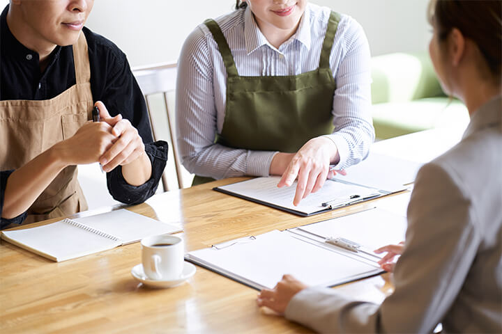 Three people sit at a desk to talk about their futures.