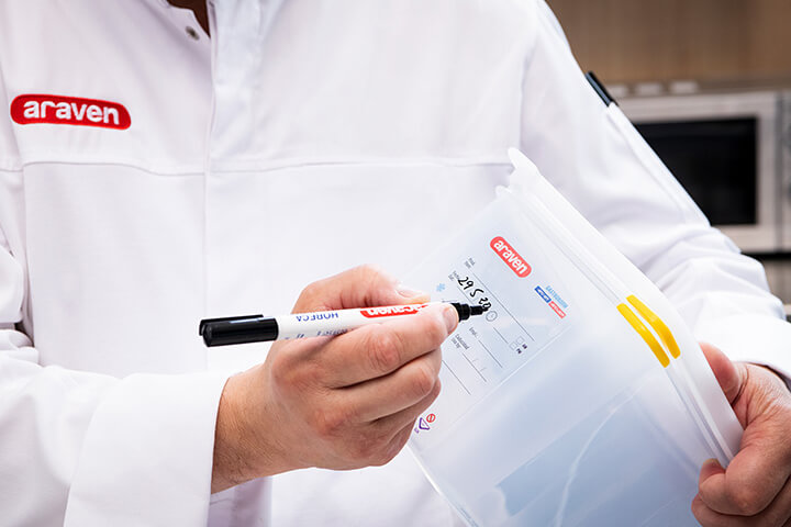 A worker writes on an Araven container with a washable pen by Araven.