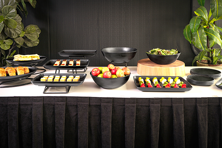 A table with a buffet spread and a black table skirt. 