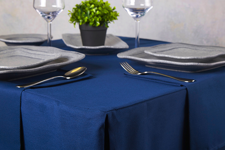A blue table cloth on a set table.