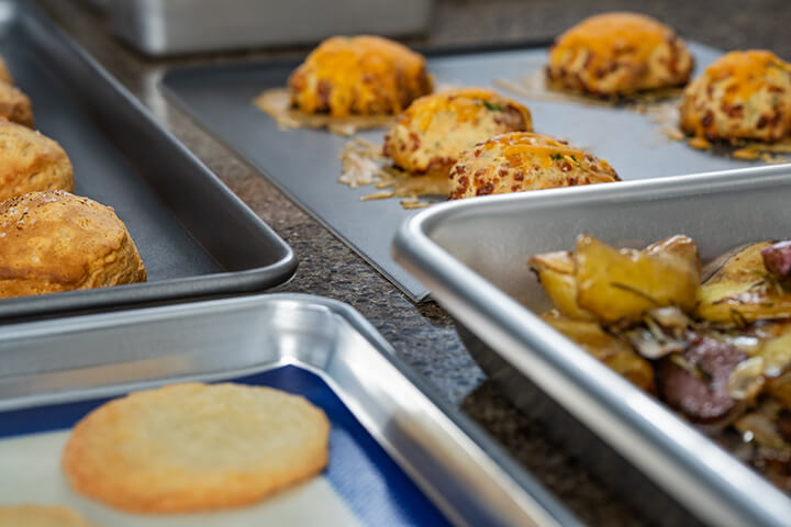 Baked muffins, cookies, and potatoes resting on Vollrath sheet pans.