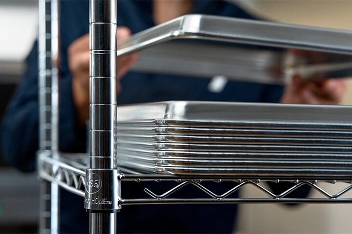 A chef grabs a Vollrath sheet pan off of a neatly stacked supply.